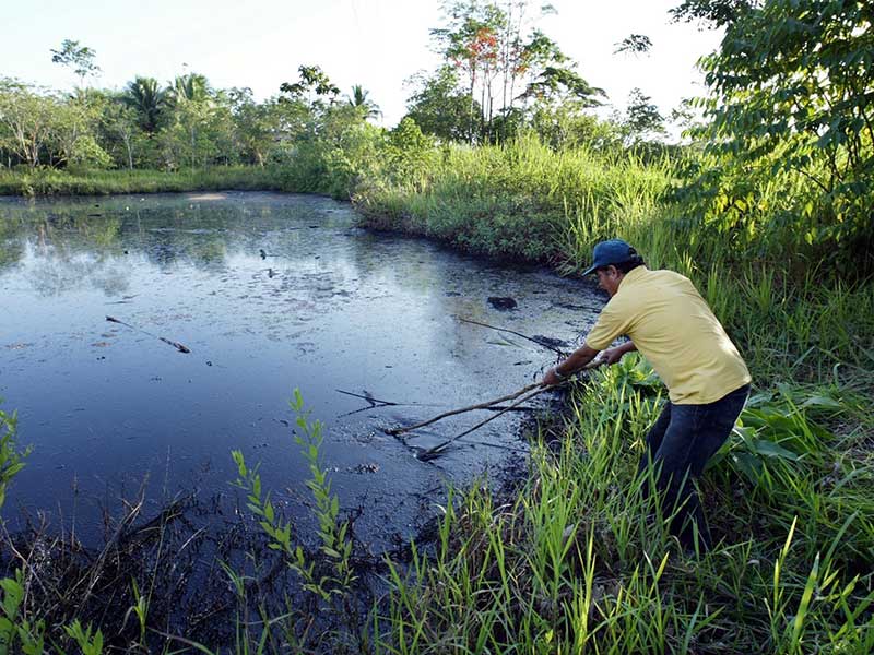 Donald Moncayo demonstrates an open oil waste pit left by Chevron in the Ecuadorian Amazon.