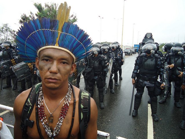 An Apiaká Indigenous leader in front of police blockade. Since 2002, a total of 448 enviromental activists have been assassinated in Brazil, making the 2014 World Cup by and far the worst place to be an environmental activist. Photo Credit: Brent Millikan/International Rivers.