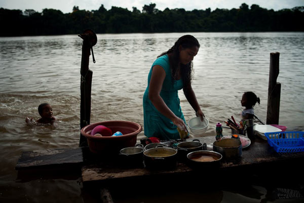 The life of the inhabitants of Pimental is integrated with the Tapajós: washing dishes in the river helps to attract fish. Photo credit: Marcio Isensee e Sá